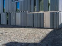 cobblestone driveway surrounded by modern buildings on sunny day with sun reflecting onto the windows