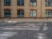 a brick courtyard has steps leading up to it, and a blue umbrella is on the ground