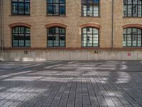 a brick courtyard has steps leading up to it, and a blue umbrella is on the ground