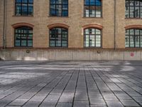 a brick courtyard has steps leading up to it, and a blue umbrella is on the ground