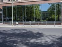 a couple of people standing on the sidewalk by a building while riding a bike near it