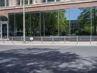 a couple of people standing on the sidewalk by a building while riding a bike near it