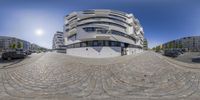 a fish eye lens looking out at the city street with parking spaces and large buildings