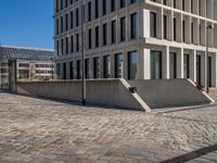 the large office building is located in the center of a cobblestone plaza of the city