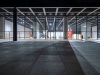 a view of a large open space with concrete flooring and windows and lights on