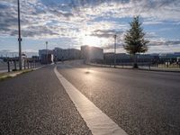 a motorcycle is going down the road by the water at sunset, next to an empty street