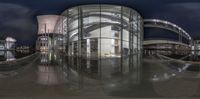 a panoramic photo of the inside of a building at night with reflectioning windows