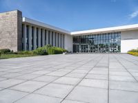 a large concrete courtyard area with benches and chairs in front of it and blue skies in the background