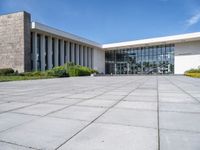 a large concrete courtyard area with benches and chairs in front of it and blue skies in the background