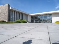 a large concrete courtyard area with benches and chairs in front of it and blue skies in the background