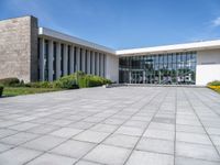 a large concrete courtyard area with benches and chairs in front of it and blue skies in the background