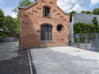 a red brick building with a gated area outside it with a green gate behind it