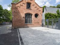 a red brick building with a gated area outside it with a green gate behind it