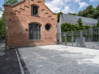 a red brick building with a gated area outside it with a green gate behind it