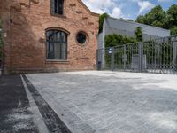 a red brick building with a gated area outside it with a green gate behind it