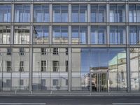 a large building is reflected in the side of the street that goes along this narrow road