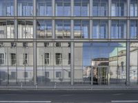 a large building is reflected in the side of the street that goes along this narrow road