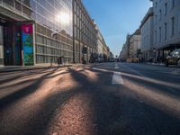 the sunlight reflects from several windows in a large building onto the street from outside the building