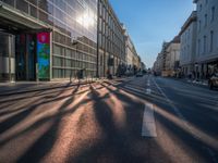 the sunlight reflects from several windows in a large building onto the street from outside the building