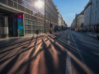 the sunlight reflects from several windows in a large building onto the street from outside the building