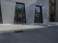 man in red coat on cellphone while riding down the sidewalk with large window reflecting behind him