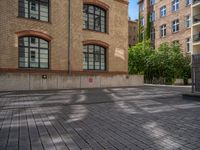 a brick courtyard has steps leading up to it, and a blue umbrella is on the ground