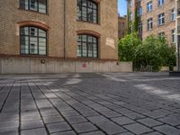 a brick courtyard has steps leading up to it, and a blue umbrella is on the ground