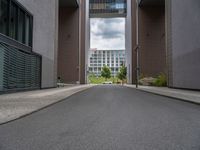 a long paved street with a building in the background and tall buildings outside each, both showing doors