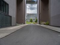 a long paved street with a building in the background and tall buildings outside each, both showing doors