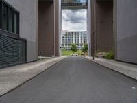 a long paved street with a building in the background and tall buildings outside each, both showing doors