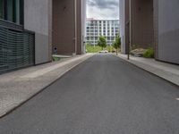 a long paved street with a building in the background and tall buildings outside each, both showing doors