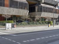 street sign next to an empty road and a tall building with many stories in the background