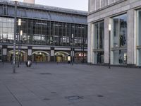 a large stone ground has many windows and benches in it, and people are seated at the benches