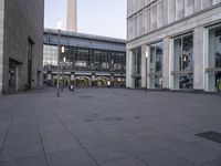 a large stone ground has many windows and benches in it, and people are seated at the benches