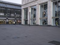 a large stone ground has many windows and benches in it, and people are seated at the benches