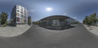 a fish - eye lens photo of an open air parking space that houses a large building