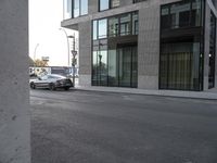 a car parked next to a street curb with a building in the background and one behind it