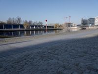 two benches in the street by a canal with buildings in the background in the city