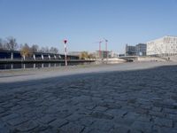 two benches in the street by a canal with buildings in the background in the city