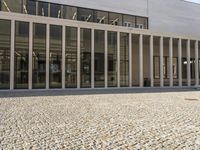 an image of an empty building on the ground with people sitting on benches in front