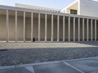 an empty courtyard with multiple columns that are filled with bricks and stone steps, at a building structure