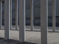 some very long and tall concrete pillars in front of a building with an umbrella on top