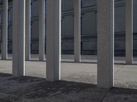 some very long and tall concrete pillars in front of a building with an umbrella on top