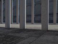 some very long and tall concrete pillars in front of a building with an umbrella on top