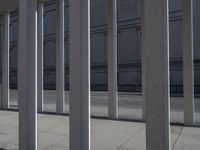 some very long and tall concrete pillars in front of a building with an umbrella on top