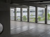 an empty building with doors that lead to a courtyard area, with some trees in the foreground