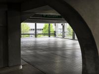 the ground is littered with gray tiles and signs on it is dark, empty, with trees in the background