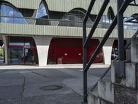 a building with glass windows and some steps outside it that has an umbrella in front