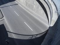 the freeway going under an overpass is empty, and a man rides his bike on it