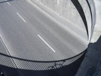 the freeway going under an overpass is empty, and a man rides his bike on it